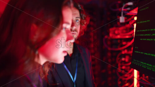 Royalty free stock video A man and a woman trying to fix an error in a server room with flashing red lights - Starpik