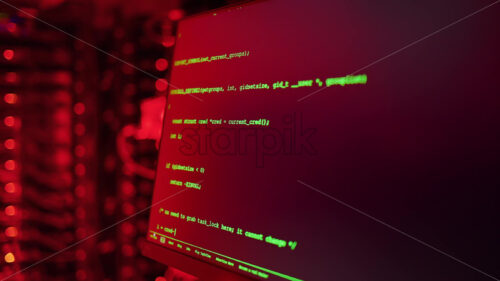 Royalty free stock video Close up of code on a screen in a server room with flashing red lights - Starpik