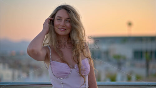 Royalty free stock video Woman in pink dress posing with the beach on the background in the evening in Cannes, France - Starpik