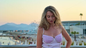 Royalty free stock video Woman in pink dress posing with the beach on the background in the evening in Cannes, France - Starpik