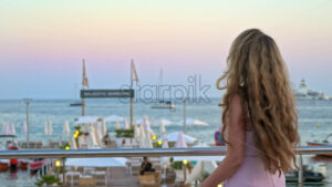 Royalty free stock video Woman in pink dress posing with the beach on the background in the evening in Cannes, France - Starpik