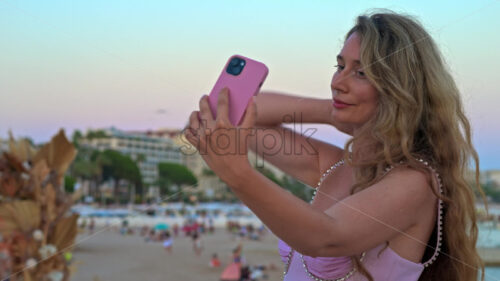 Royalty free stock video Woman in pink dress taking pictures at the beach in the evening in Cannes, France - Starpik