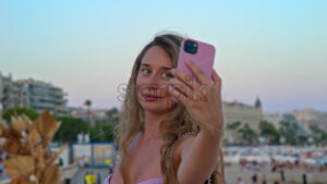 Royalty free stock video Woman in pink dress taking pictures at the beach in the evening in Cannes, France - Starpik