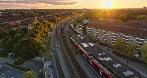 Video Aerial drone view of a train moving on the tracks near Vesterbro district in Copenhagen, Denmark at sunset - Starpik