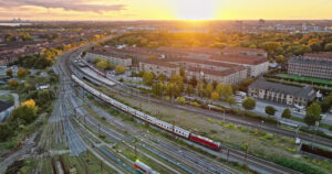 Video Aerial drone view of a train moving on the tracks near Vesterbro district in Copenhagen, Denmark at sunset - Starpik