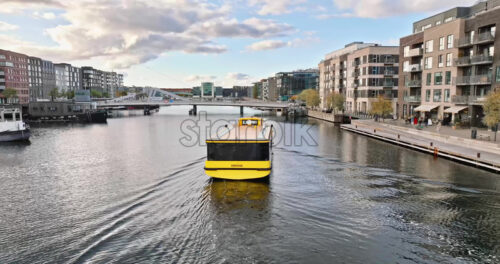 Video Aerial drone view of a yellow boat moving on the water in the Teglholmen peninsula in the South Harbour of Copenhagen, Denmark - Starpik