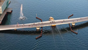 Video Aerial drone view of a yellow boat moving on the water under the Quay Bridge across the port of Copenhagen, Denmark in the evening - Starpik