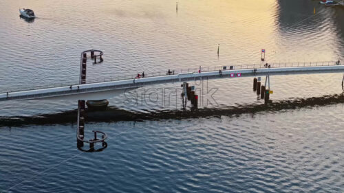 Video Aerial drone view of people moving on the Quay Bridge across the port of Copenhagen, Denmark in the evening - Starpik