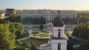 Aerial drone view of Chisinau downtown at sunset. Panorama view of Goverment building, Triumph Arch, bell tower, moving cars. Moldova - Starpik