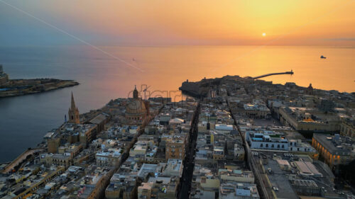 VIDEO Aerial drone view of the walled city of Valletta, Malta, surrounded by the Mediterranean sea in the evening - Starpik