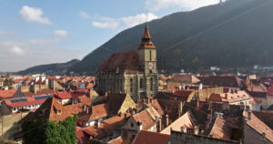 Video Aerial drone view of The Black Church in the city center of Brasov, Romania surrounded by mountains - Starpik