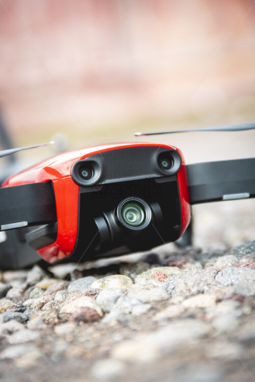 A small red drone placed on the pebbles for the take off. Close up shot - Starpik