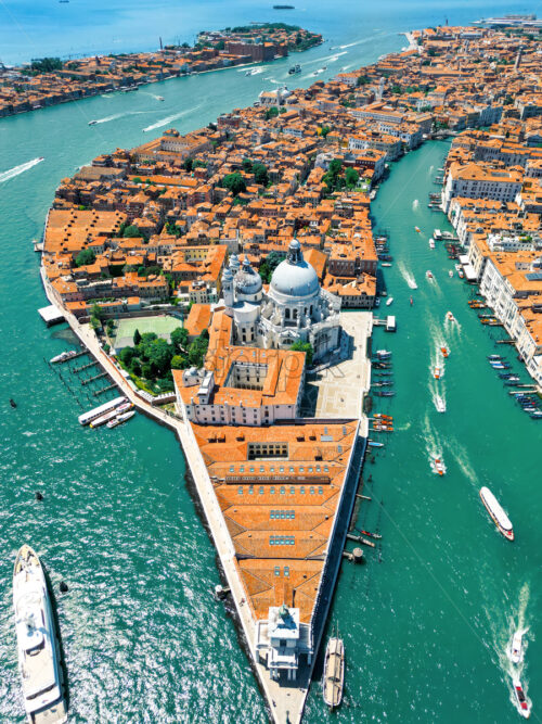 Aerial drone view of Venice, Italy. Water channels with multiple floating and moored boats, historical city centre with Santa Maria della Salute and other old buildings and narrow streets - Starpik