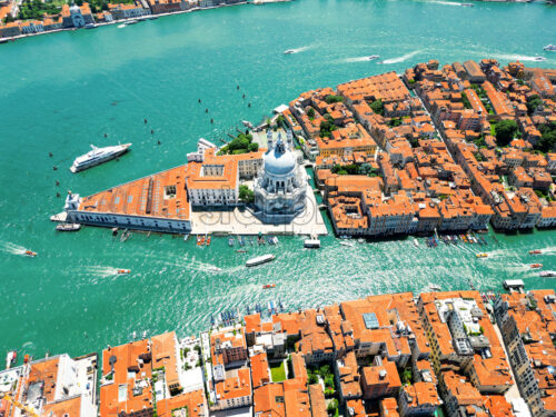 Aerial drone view of Venice, Italy. Water channels with multiple floating and moored boats, historical city centre with Santa Maria della Salute and other old buildings and narrow streets - Starpik