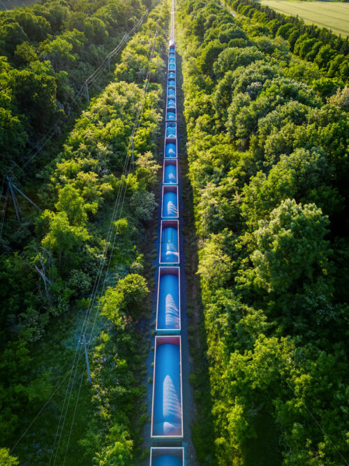 Aerial drone view of a moving train on railway with lush greenery around it in Moldova - Starpik