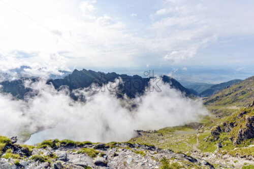 Balea Lake with clouds above from top view. Bright blue sky on background. Fagaras Mountains, Romania - Starpik