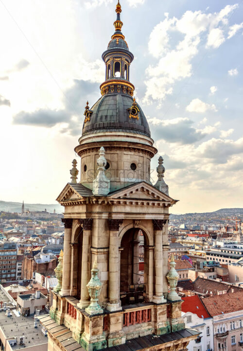 Bell Tower of St. Stephen’s Basilica at sunset. Warm sky with clouds and city on background. Negative copy space, place for text. Budapest, Hungary - Starpik