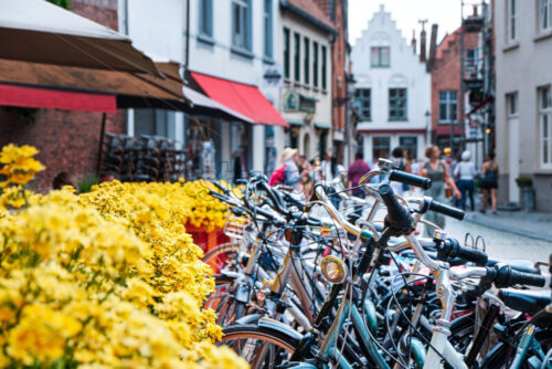 Bicycles parked near yellow flowers. Bruges city on background. Belgium - Starpik