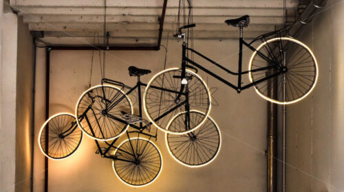 Bikes with illuminated wheels hanging from ceiling in interior. Bruges, Belgium - Starpik