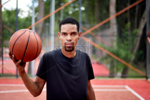 Black basketball player playing in the field at daylight - Starpik