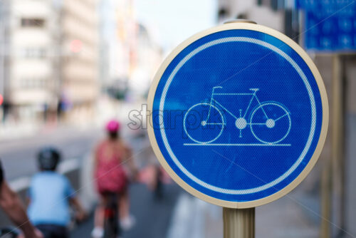 Blue street bike sign on the road, family with kids cycling on special way in Brussels, Belgium - Starpik