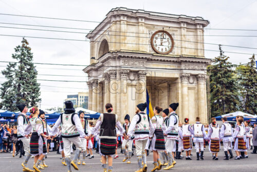 CHISINAU, MOLDOVA – OCTOBER 14, 2017: People dancing national Hora dance near Arch of Triumph at city day. Clouds on background - Starpik