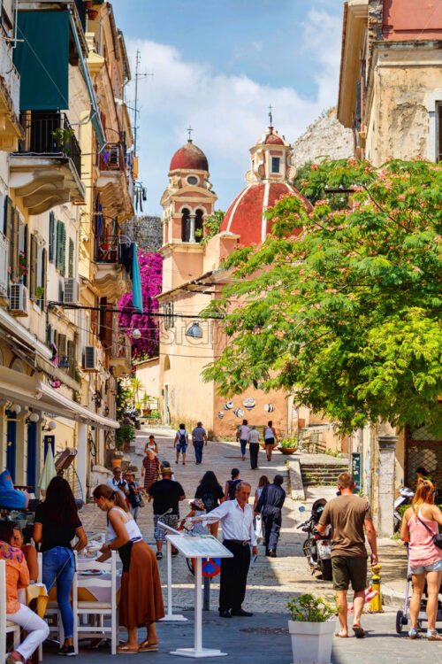 CORFU ISLAND, GREECE – JUNE 26, 2017: Narrow tourist street with people walking. Corfu city, Greece. Daylight view - Starpik