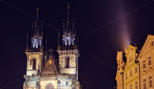 Church of Our Lady before Tyn in Old Town square at night. Buildings on sides. Bright lights pointing on facade. Negative copy space, place for text. Prague, Czech Republic - Starpik