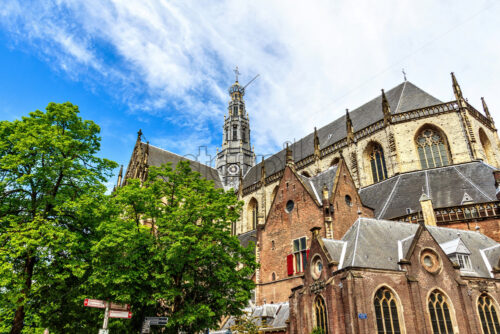 Church of St. Bavo from bottom in a sunny day. Bright blue sky with clouds on background. Negative copy space, place for text. Haarlem, The Netherlands - Starpik