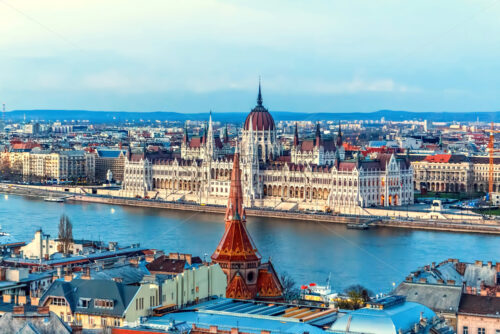 City and Danube River at sunset. Blue cold sky on background and warm sunlight reflecting on buildings. Parliament on background. Negative copy space, place for text. Budapest, Hungary - Starpik