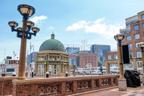 Cityscape in Boston with moored ships in the foreground and modern buildings in the background, the weather is sunny and clear - Starpik