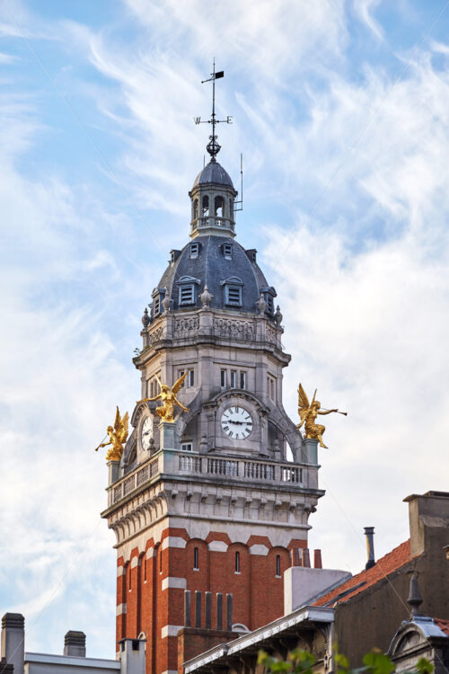 Clock tower in Saint-Gilles municipality. Close-up shot. Cloudy sky on background. Brussels, Belgium - Starpik