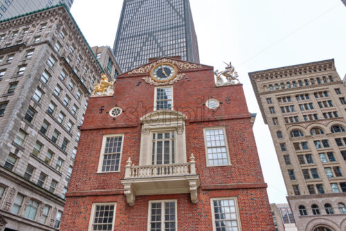 Close-up shot of the Old State House in Boston with aged and high modern building in the background, the sky behind the main scene is gray and cloudy - Starpik