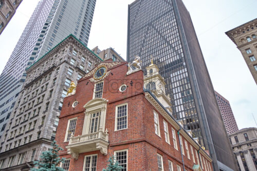 Close-up shot of the Old State House in Boston with aged and high modern building in the background, the sky behind the main scene is gray and cloudy - Starpik