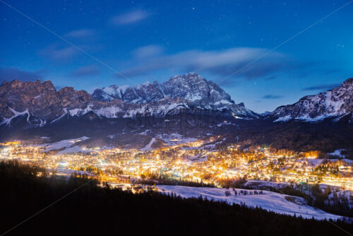 Cortina Ampezzo ski resort city at night. Mountains covered in snow on background. Province of Belluno, Italy - Starpik