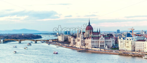 Cruise ships at sunset on Danube river. Warm sky reflecting on water. Famous parliament and city on background. Budapest, Hungary - Starpik