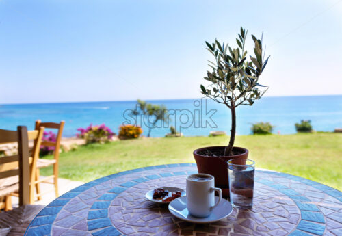 Cup of coffee on a table with olive tree, with the sea view and sky in protaras, cyprus island. - Starpik