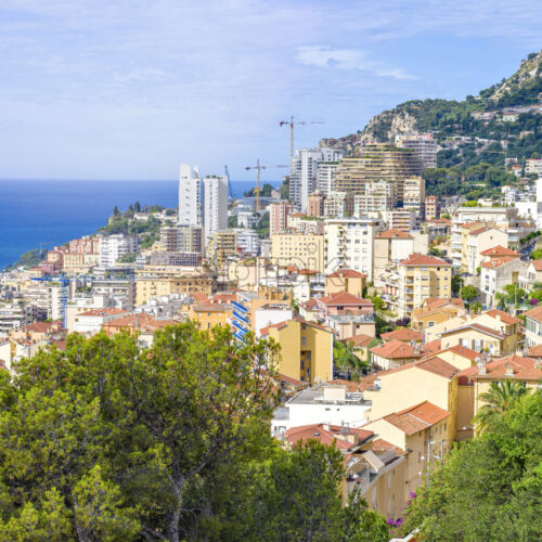 Daylight portrait view from top to city buildings and green mountains on background. Historical architecture. Parked cars on streets. Negative copy space, place for text. Monte Carlo, Monaco - Starpik