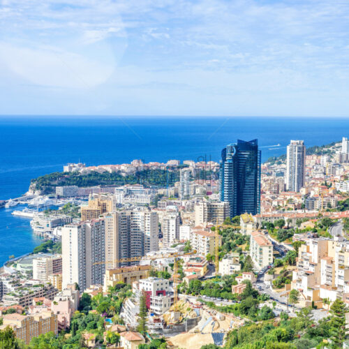 Daylight portrait view from top to modern tall city buildings. Port with yachts, bright blue sky and green mountains on background. Negative copy space, place for text. Monte Carlo, Monaco - Starpik