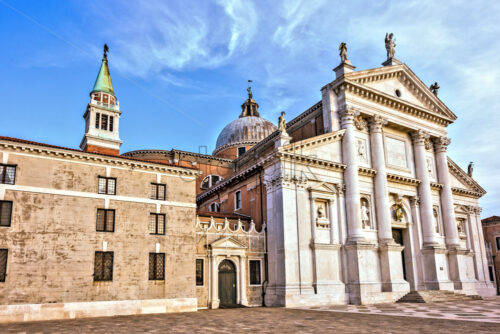 Daylight side view to San Giorgio Maggiore church facade with entrance. Bright blue sky with clouds on background. Negative copy space, place for text. Venice, Italy - Starpik