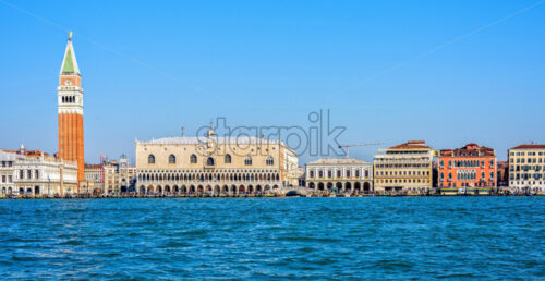 Daylight view from boat to Riva degli Schiavoni waterfront and colorful tall buildings. Bright blue clear sky. Negative copy space, place for text. Venice, Italy - Starpik