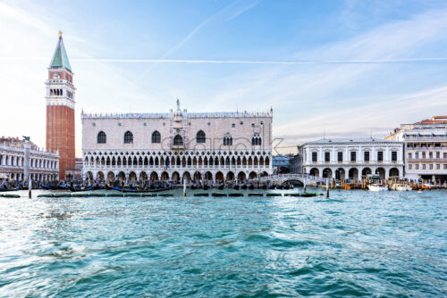 Daylight view from boat to Riva degli Schiavoni waterfront and colorful tall buildings. Bright blue sky with plane traces and clouds. Negative copy space, place for text. Venice, Italy - Starpik