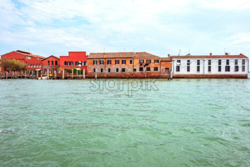 Daylight view from boat to historic architecture buildings in sunny day. Bright blue sky with clouds on background. Light reflecting on water. Negative copy space, place for text. Venice, Italy - Starpik