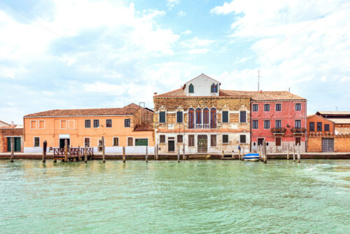 Daylight view from boat to historic architecture buildings in sunny day. Bright blue sky with clouds on background. Light reflecting on water. Negative copy space, place for text. Venice, Italy - Starpik