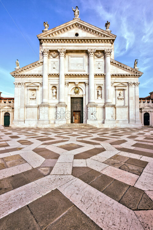 Daylight view from bottom to front facade of San Giorgio Maggiore church with entrance. Bright blue sky with clouds on background. Negative copy space, place for text. Venice, Italy - Starpik