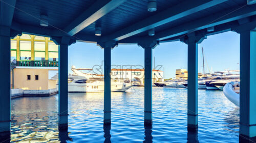 Daylight view from dark awning to parked luxury yachts and restaurants on background. Bright blue clear sky. Limassol, Cyprus - Starpik