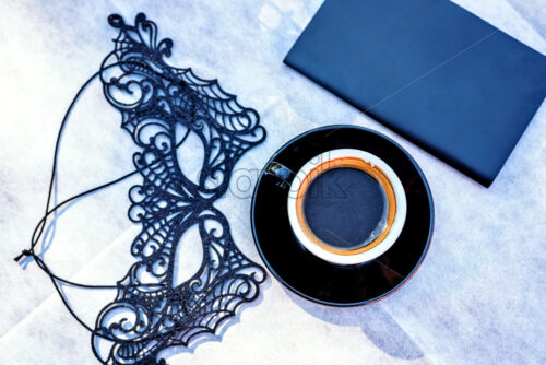 Daylight view from top to a table with black coffee cup, black mask and notebook. Negative copy space, place for text. Burano, Italy - Starpik