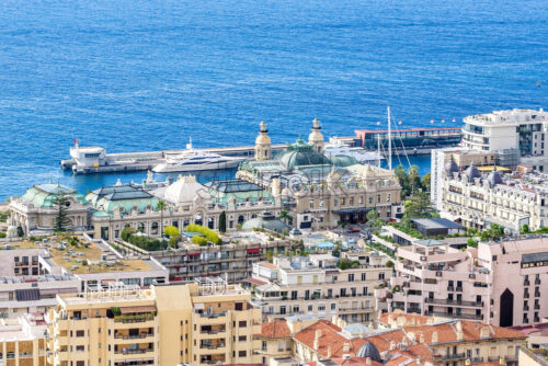 Daylight view from top to city buildings and port with parked yacht. Bright blue clear water and sky on background. Negative copy space, place for text. Monte Carlo, Monaco - Starpik