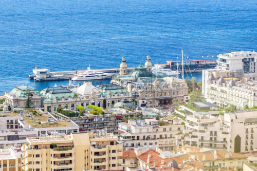 Daylight view from top to city buildings and port with parked yacht. Bright blue clear water and sky on background. Negative copy space, place for text. Monte Carlo, Monaco - Starpik