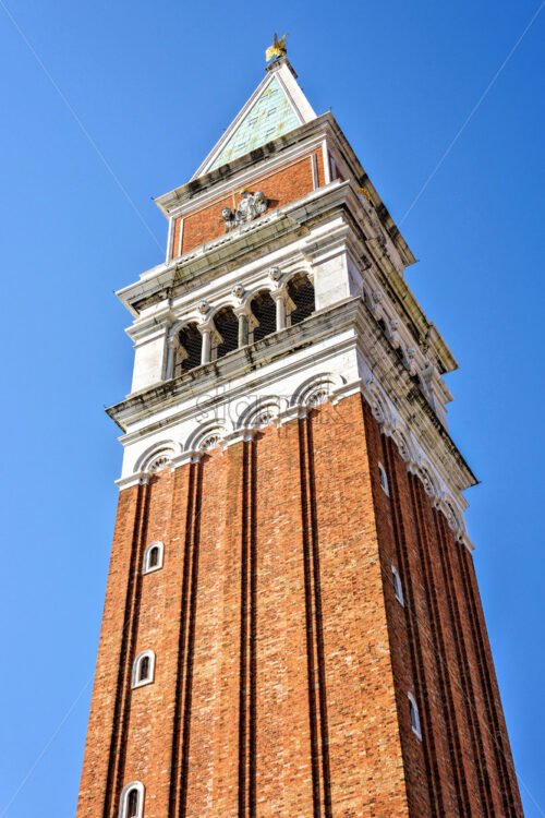 Daylight view to Saint Mark’s Campanile bell tower isolated from San Marco square. Bright blue clear sky. Negative copy space, place for text. Venice, Italy - Starpik